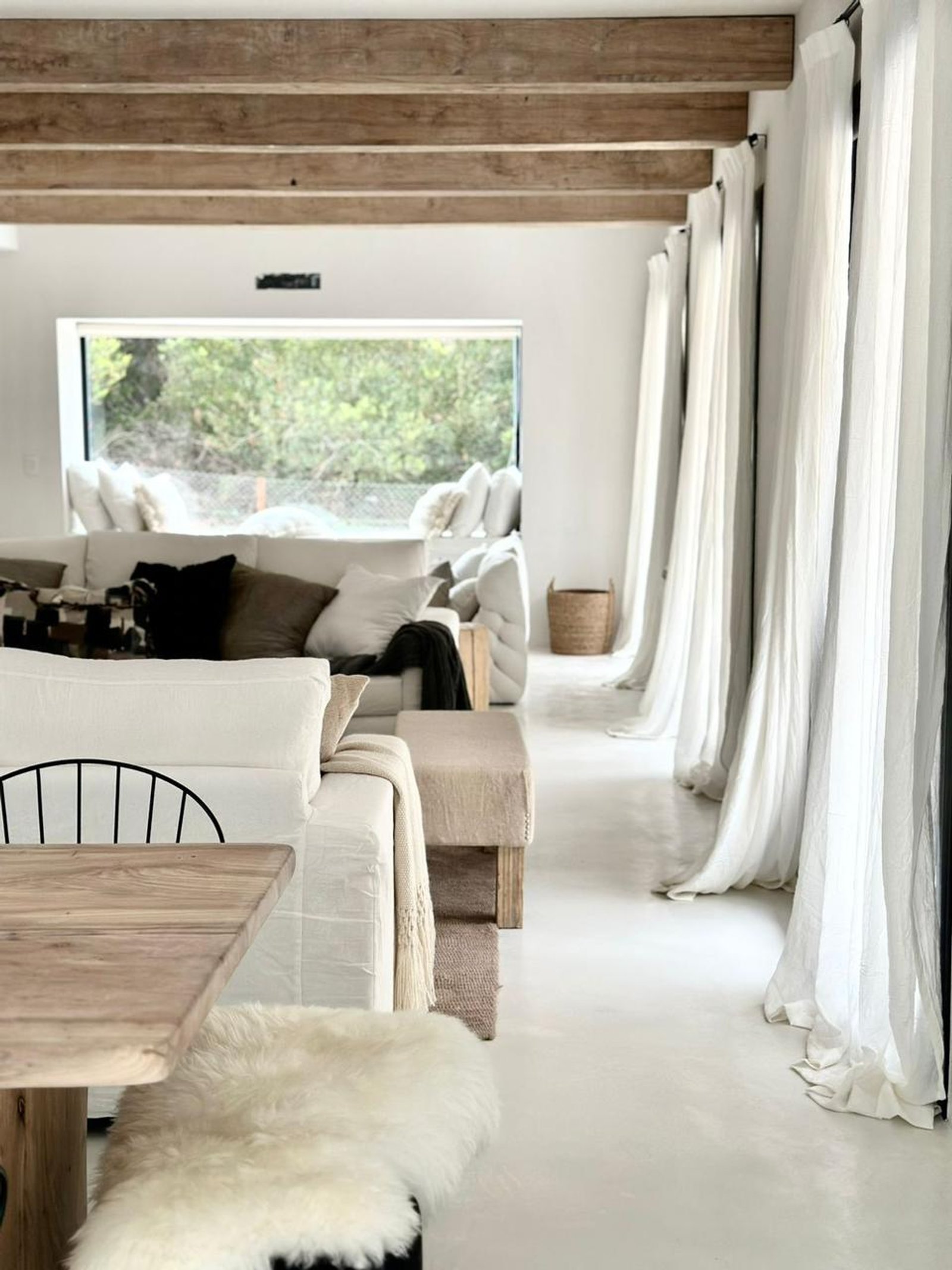 Sala minimalista con vigas de madera expuesta y ventana al bosque — proyecto CE, por arquitectura.JD, en Pinamar